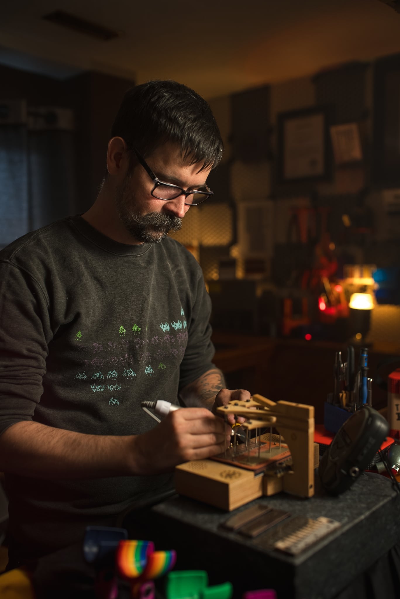 Rob Laferriere, owner of Woozle Harmonicas, tuning a reedplate on a Masterharp Tuning Table, using a rotary polisher. He’s wearing a well worn “Harp Invaders” sweater that is available for purchase here on this website.